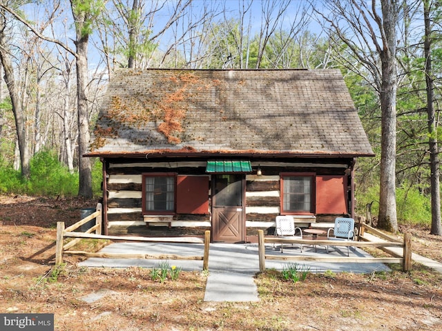 chalet / cabin featuring an outbuilding, roof with shingles, and log exterior