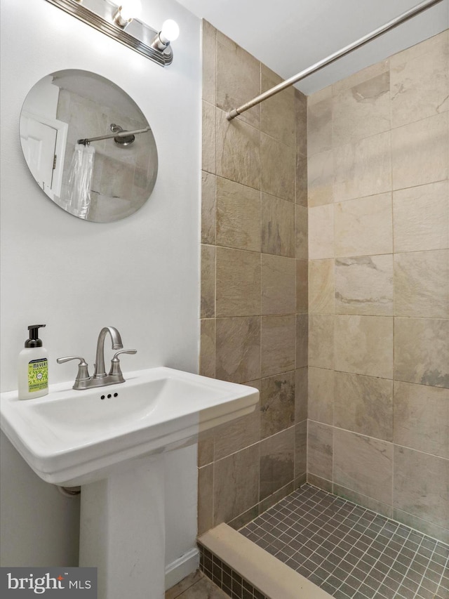 full bath with a sink and a tile shower