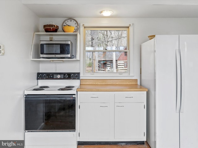 kitchen with white cabinetry, light countertops, and white appliances