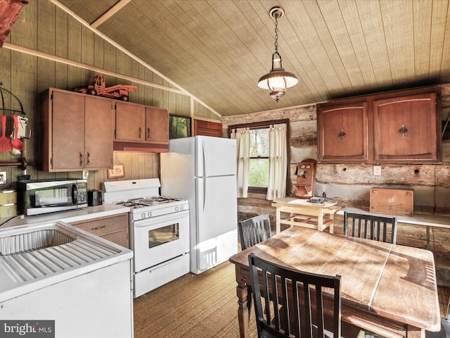kitchen featuring light countertops, white appliances, lofted ceiling, a sink, and decorative light fixtures
