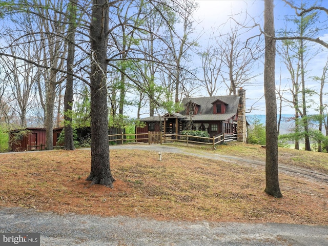 view of front of house featuring aphalt driveway, fence, and a chimney