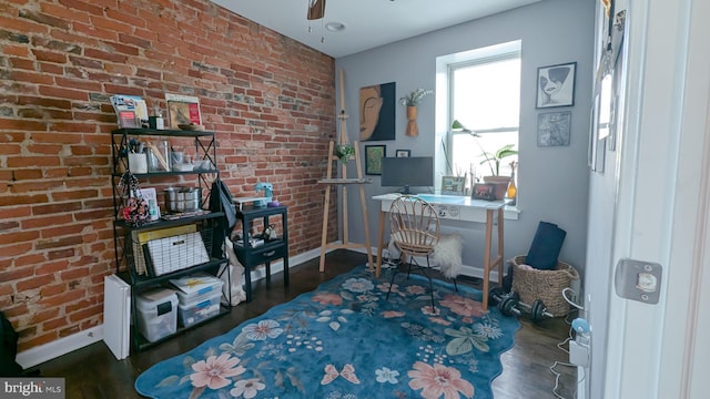 office space with baseboards, brick wall, and wood finished floors