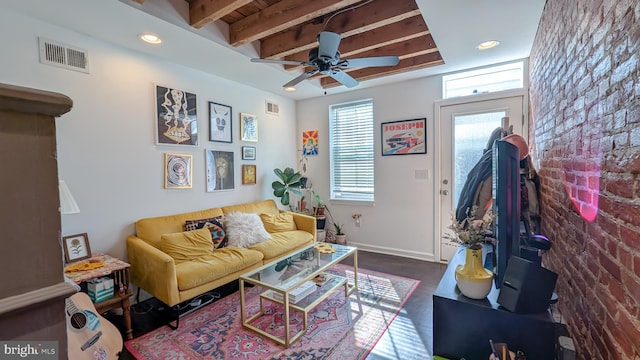 living room with baseboards, visible vents, beamed ceiling, and brick wall