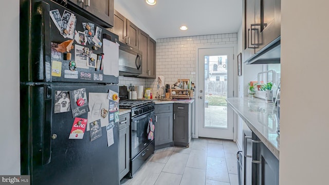 kitchen with light stone counters, tasteful backsplash, recessed lighting, a sink, and black appliances