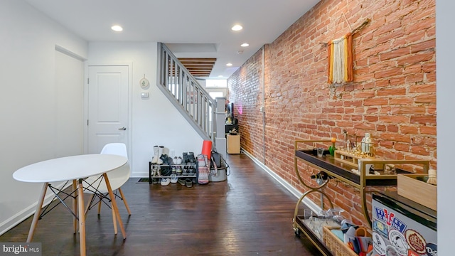 interior space featuring brick wall, stairs, baseboards, and wood finished floors