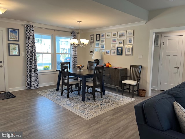 dining area with baseboards, ornamental molding, wood finished floors, and an inviting chandelier