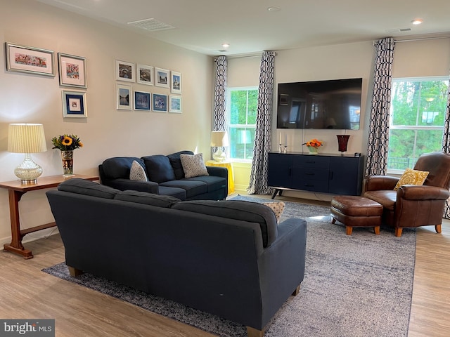 living area with wood finished floors, visible vents, and a healthy amount of sunlight