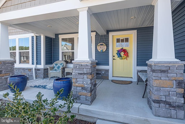 doorway to property with stone siding and covered porch