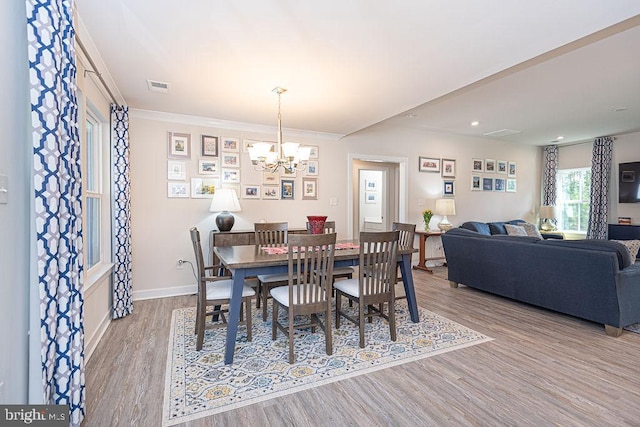 dining room with visible vents, ornamental molding, wood finished floors, a chandelier, and baseboards