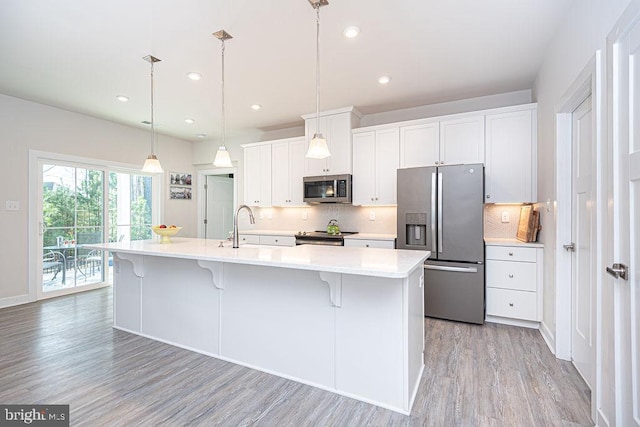 kitchen featuring tasteful backsplash, white cabinets, appliances with stainless steel finishes, light countertops, and a sink