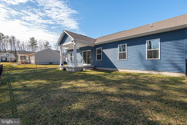 back of property with a shingled roof, fence, and a lawn