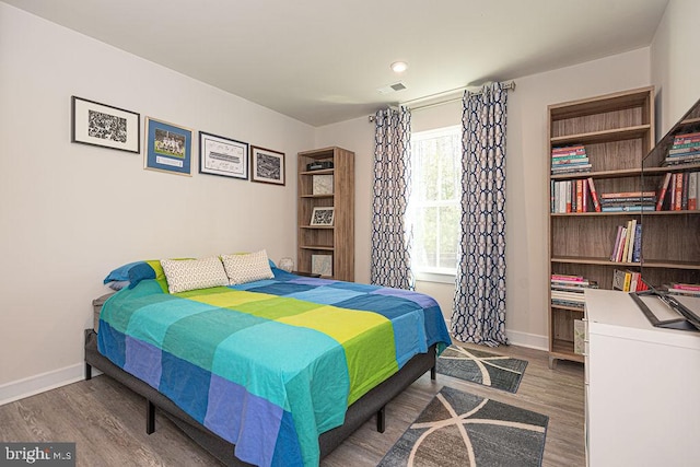 bedroom featuring visible vents, baseboards, and wood finished floors