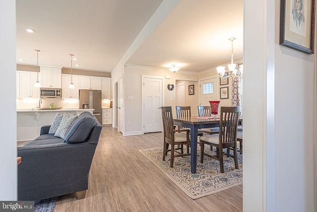 dining room featuring crown molding, recessed lighting, light wood-style flooring, a chandelier, and baseboards