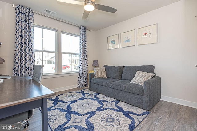 living room with a ceiling fan, visible vents, baseboards, and wood finished floors