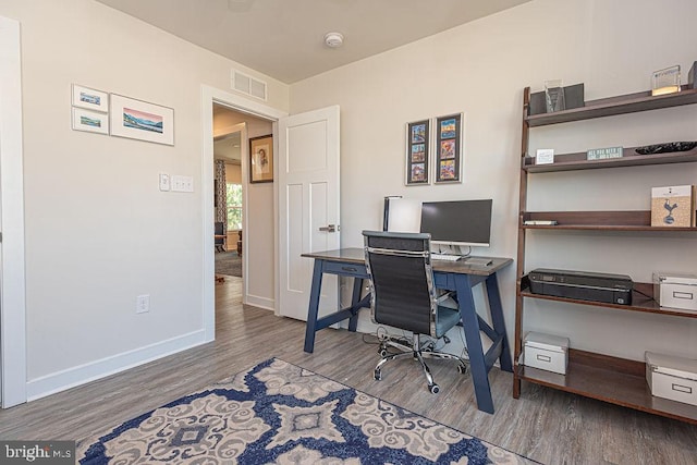 office area featuring visible vents, baseboards, and wood finished floors