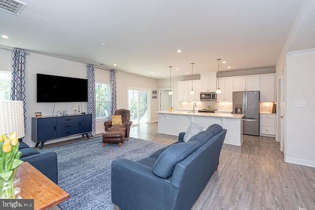 living room featuring recessed lighting, baseboards, visible vents, and light wood finished floors