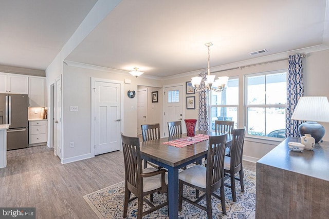 dining area featuring light wood-type flooring, baseboards, a chandelier, and ornamental molding