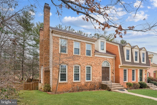 view of front of property with a front yard, a chimney, fence, and brick siding