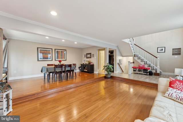 living room featuring stairs, crown molding, recessed lighting, baseboards, and hardwood / wood-style flooring