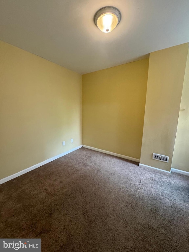 spare room featuring carpet, visible vents, and baseboards