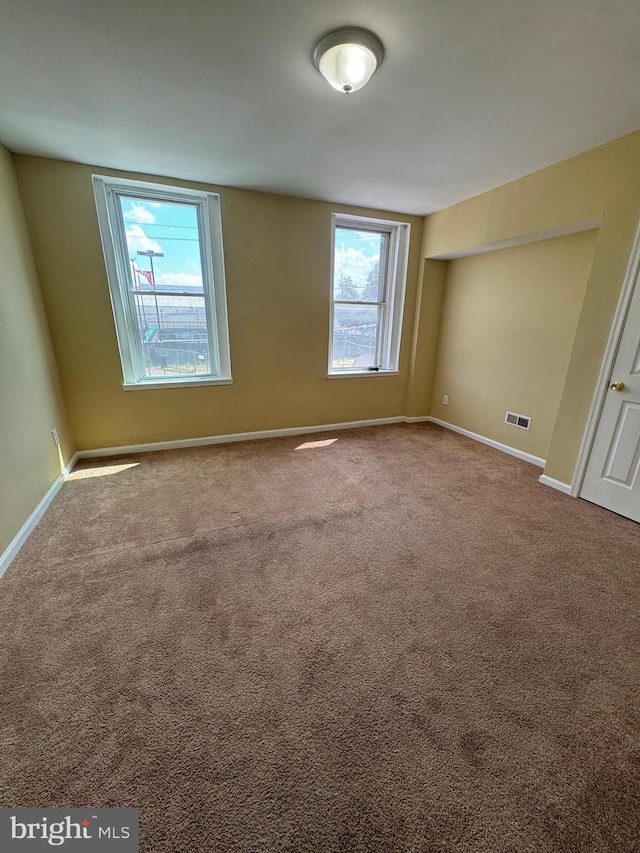 carpeted spare room with visible vents and baseboards