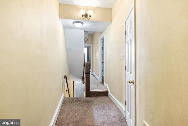 corridor with carpet floors, baseboards, and an upstairs landing