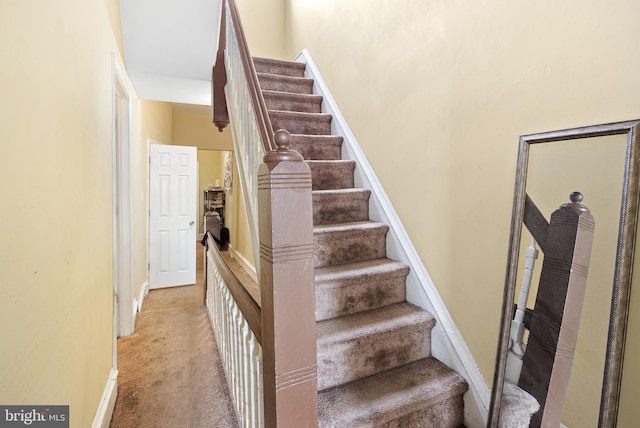 stairway featuring carpet floors and baseboards