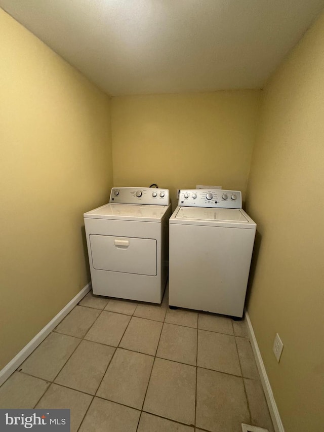 laundry area with light tile patterned floors, laundry area, washing machine and clothes dryer, and baseboards