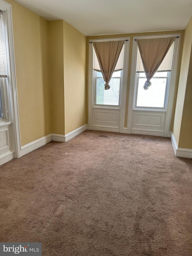 unfurnished room with plenty of natural light, carpet, and baseboards