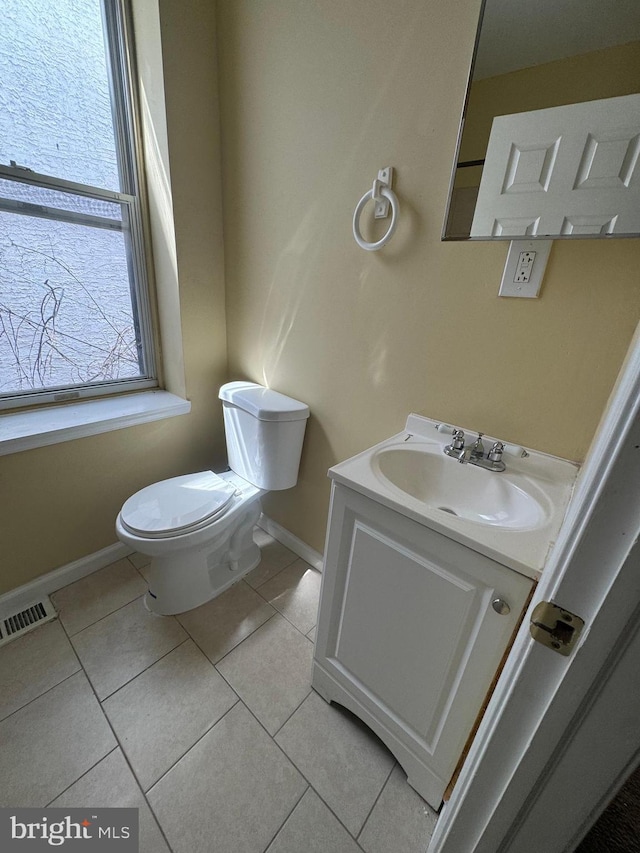 half bathroom with visible vents, toilet, vanity, baseboards, and tile patterned floors