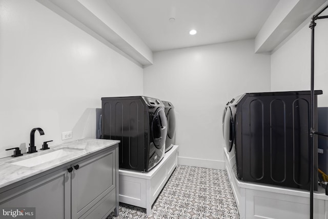 laundry area featuring cabinet space, washing machine and dryer, a sink, baseboards, and tile patterned floors