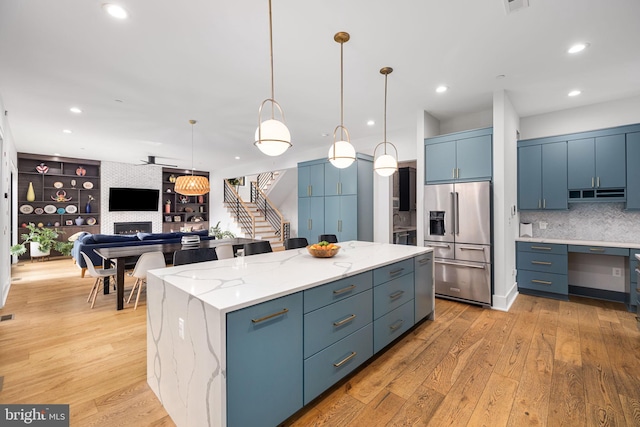 kitchen featuring light wood-style floors, a fireplace, high quality fridge, and a kitchen island