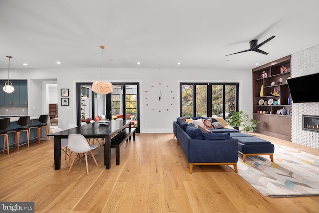 living area with light wood-style floors, built in features, a large fireplace, and french doors