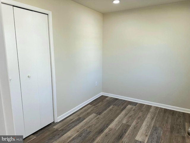 unfurnished bedroom with recessed lighting, a closet, dark wood finished floors, and baseboards