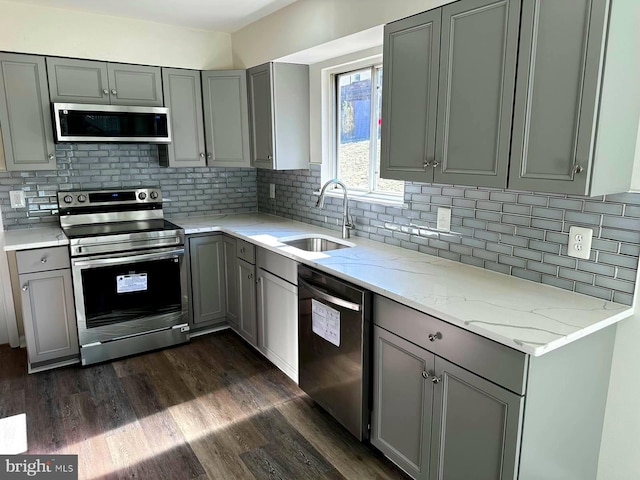 kitchen with dark wood-style floors, appliances with stainless steel finishes, a sink, and gray cabinetry