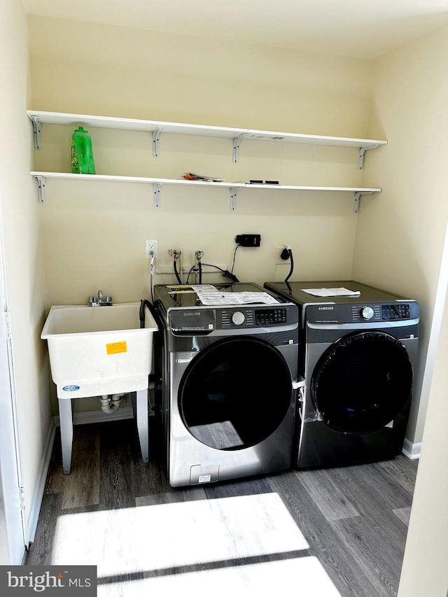 laundry area with laundry area, baseboards, washing machine and clothes dryer, and wood finished floors