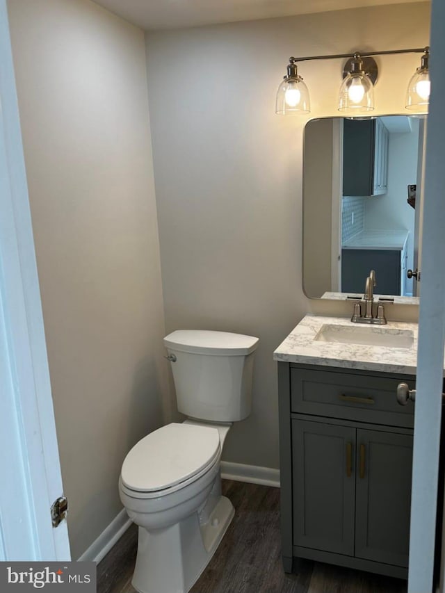 bathroom featuring vanity, wood finished floors, toilet, and baseboards