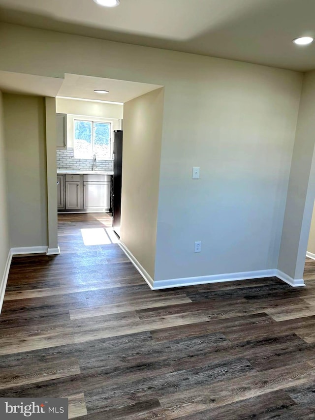 hall with recessed lighting, dark wood-style flooring, a sink, and baseboards