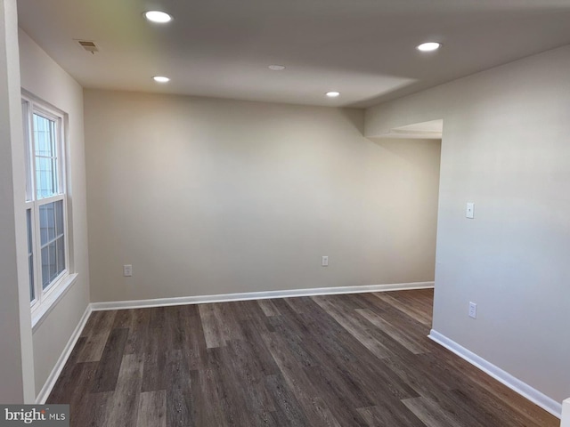 empty room featuring visible vents, baseboards, dark wood finished floors, and recessed lighting