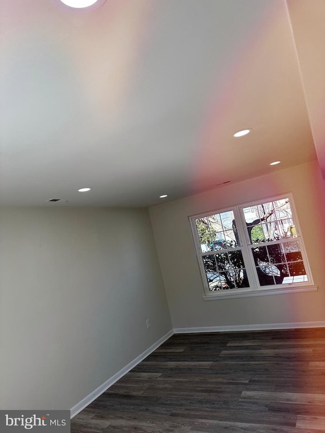 spare room featuring dark wood-style flooring, recessed lighting, and baseboards