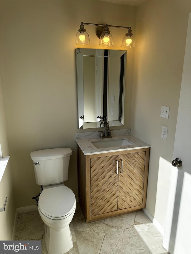 half bath with marble finish floor, baseboards, vanity, and toilet