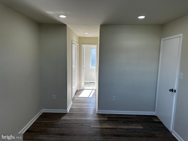 corridor featuring baseboards, dark wood finished floors, and recessed lighting