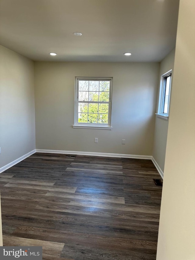 unfurnished room with a wealth of natural light, visible vents, and baseboards