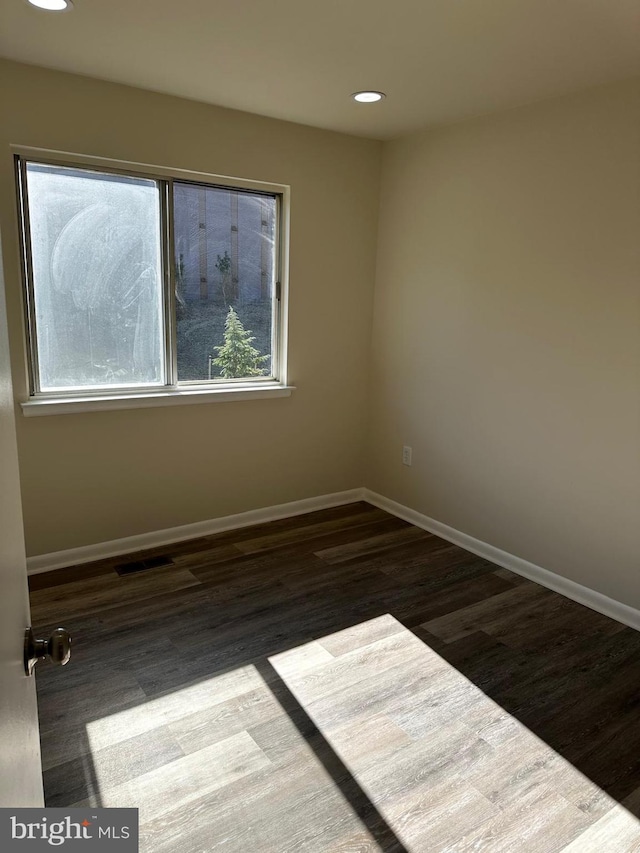 empty room with recessed lighting, wood finished floors, visible vents, and baseboards