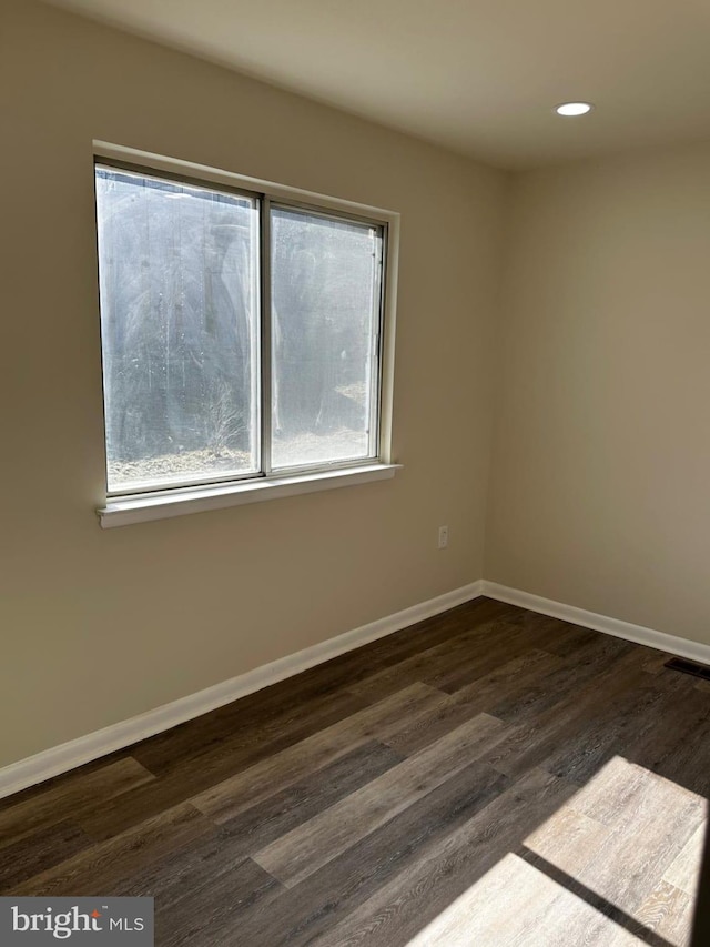 empty room featuring recessed lighting, dark wood finished floors, visible vents, and baseboards