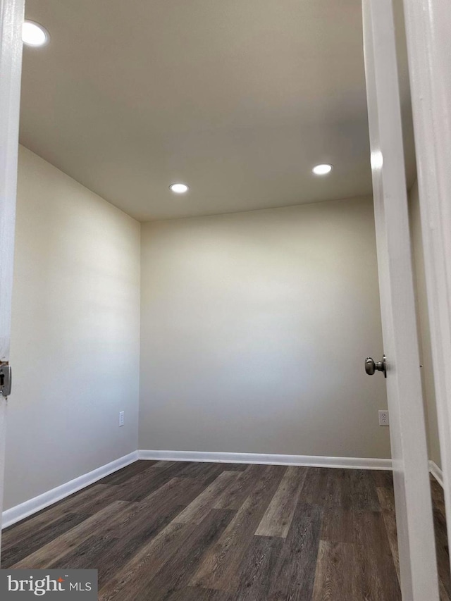 empty room with dark wood-type flooring and baseboards