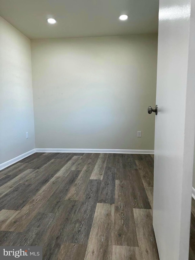 empty room with dark wood-style flooring, recessed lighting, and baseboards