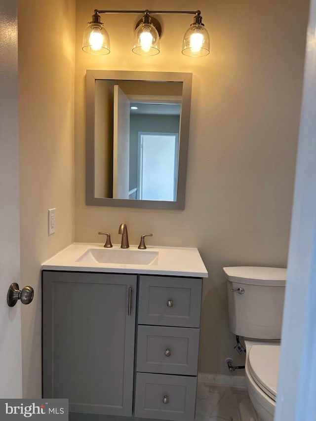 half bath featuring toilet, marble finish floor, and vanity