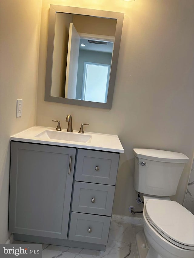 bathroom featuring toilet, marble finish floor, and vanity