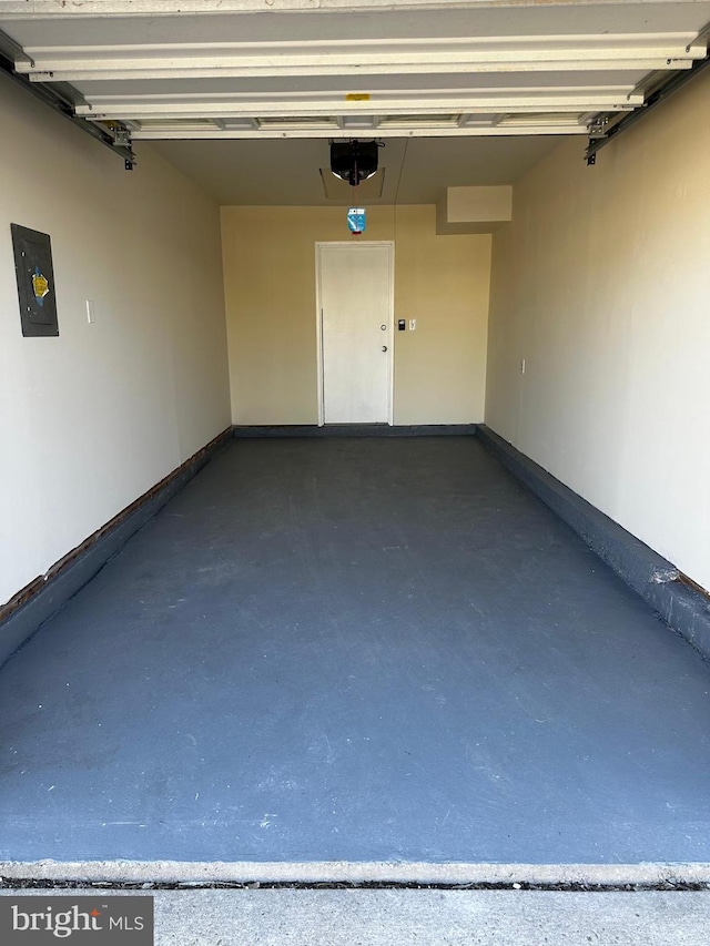 garage with a garage door opener, electric panel, and baseboards